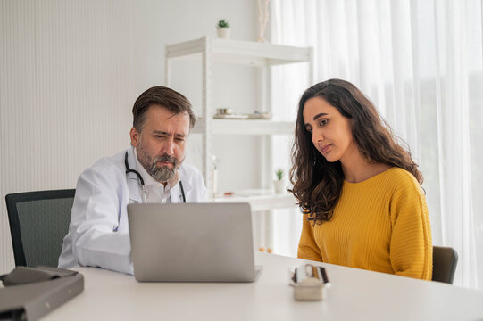 Male doctor talking to woman about illness in clinic. Caucasian docter to check up health female in examination hospital room. Healthcare and medical concept.