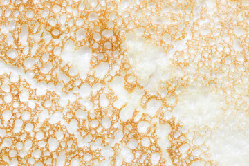 Pancake texture. Baked dough air bubbles. Food macro closeup. Fluffy pancake structure. Bubbles pattern. Spotted structure. Crepe background. Fried golden color.