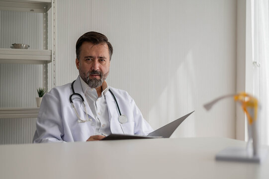 Portrait of professional doctor sitting in uniform with stethoscope in hospital. confidence smart male doctor sitting in medical examination room.