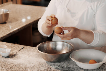 Crop anonymous female cook cracking egg into metal bowl while preparing dough for Italian pasta in kitchen