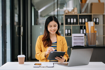 Fototapeta premium Confident business expert attractive smiling young woman typing laptop ang holding digital tablet on desk in office.