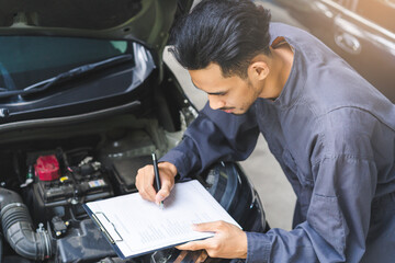 Auto check, car service shop concept. Automobile repairman writing job checklist on clipboard,...