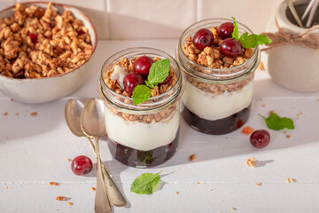 Delicious and homemade cherries granola in jar with yoghurt.