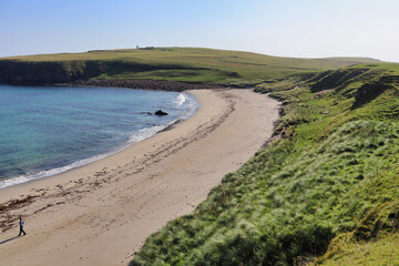 Blue water white sand scottish beach in scotland with grass and dunes