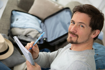 man packing suitcase with a checklist