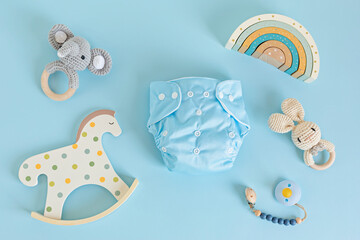 Flat lay with reusable cloth baby diaper, toys and accessories. Eco friendly nappy on blue pastel background. Sustainable lifestyle, zero waste idea - obrazy, fototapety, plakaty