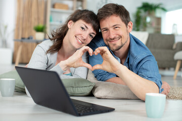 happy couple during moving house showing heart sign
