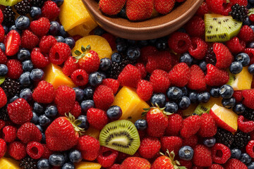 Fototapeta premium Mixed fresh fruits (strawberry, raspberry, blueberry, kiwi, mango) in a bowl, placed on table