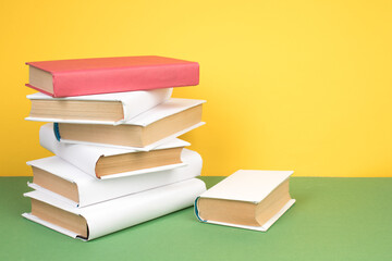 Books stacking. Open hardback books on wooden table and green background. Back to school. Copy space for ad text.