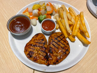 baked chicken breast served with french fries, vegetables and barbecue sauce on a ceramic plate