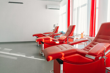 Red armchairs for sitting in donation center. Blood transfusion station for taking blood from donors
