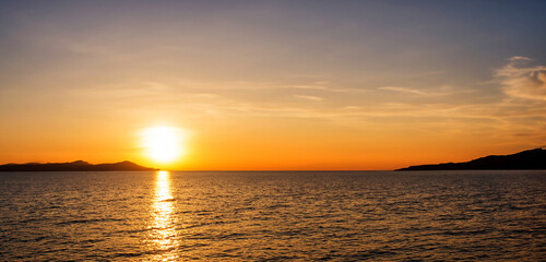 Obraz premium Beach seaside evening at sunset With rocks and hills orange sky