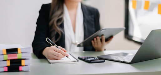 Young beautiful woman using laptop and tablet while sitting at her working place. Concentrated at work.