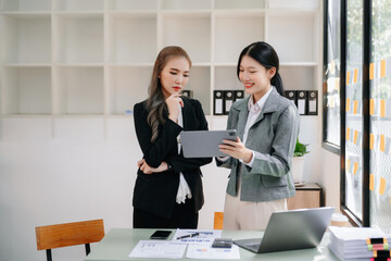 Businesswomen work and discuss their business plans. A Human employee explains and shows her colleague the results paper in office..