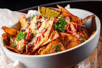 plate of delicious tortilla nachos with melted cheese sauce, ground beef, jalapeno peppers in bowl