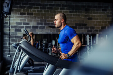 Fototapeta na wymiar Healthy young man in GYM running on treadmill