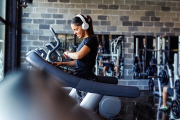 Fototapeta na wymiar Young happy athletic woman adjusting speed while running on treadmill in a gym.