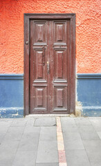 Street view of an old colonial building facade with wooden door, architecture background, Cuenca, Ecuador.