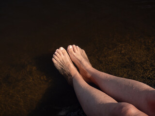 Women's feet are refreshed by bathing and splashing water in the lake. - 658981749
