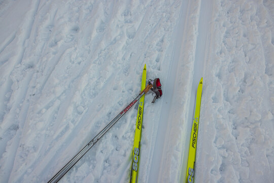 Close-up view of yellow classic plastic Fischer skis and Swix poles lying on ski track. Sweden. 