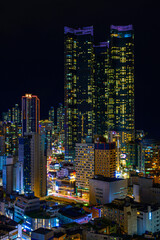 Busan City skyline, skyscrapers, and modern buildings at night, illuminated in vibrant colors over the Haeundae Beach in Kyongsang Namdo, South Korea