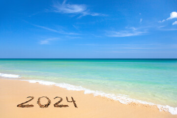 Fototapeta na wymiar 2024 written on sandy beach