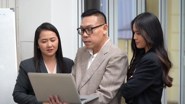 group of asian business people lgbtq manager talking and teaching woman worker with laptop computer in office.