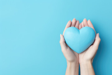 Female hands holding blue paper heart on blue background, top view with copy space