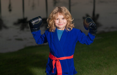 Kid boy in kimono practicing judo, taekwondo, jujitsu, kung-fu, jiu-jitsu, aikido outdoor. Sport karate kids. Little boy wearing kimono doing karate in park. Martial arts for kids.