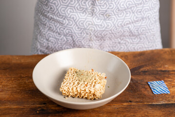 Instant noodles on a plate sprinkled with seasonings. wooden background