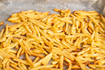 fried french fries lying on baking paper. Cooking frozen French fries in the oven