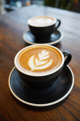 Coffee latte served in a black cup on a blurred table background