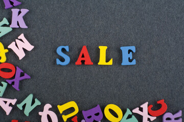 Sale word on black board background composed from colorful abc alphabet block wooden letters, copy space for ad text. Learning english concept.
