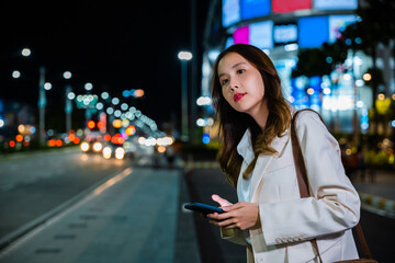 Close up of young Asian woman using mobile app device on smartphone to arrange taxi ride in city...