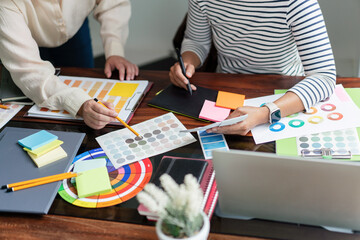 Two creative graphic designers discuss about colors swatch to designing project and draw on tablet