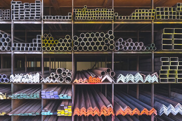 Group of various types of steel bars and pipes stacked on the storage shelf of building materials...
