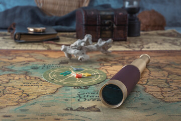 Spyglass, a branch of coral and colored markers lie on an old map