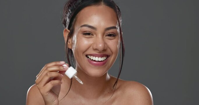 Woman, smile and serum with dropper for skincare, health and wellness in beauty at studio by gray background. Happy model, apply and face hydration for skin, cosmetics and dermatology in portrait