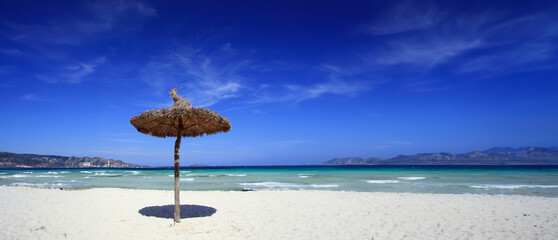 Midday Serenity: Alcudia's Straw Umbrella and Azure Expanse