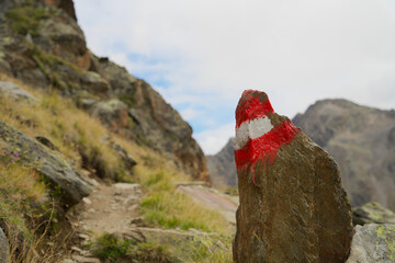 Close up of a red and white road marking on an alpine mountain trail 