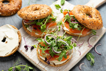 Smoked salmon and soft cheese seeded bagel with pea and purple reddish shoot salad and red onion. Protein packed breakfast concept