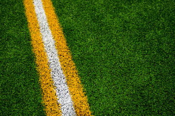Green artificial football field turf with yellow and white yard lines