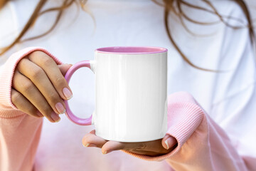 Girl is holding blank Pink Handle 11 oz white mug in hands and pink- white sweatshirt . Blank ceramic cup in hands
