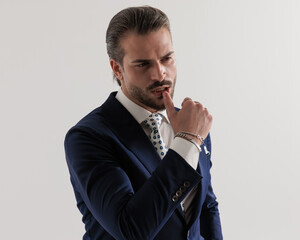 sensual elegant businessman looking away while touching lips in a seductive way