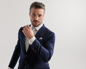sexy young businessman with glasses holding arms in fashion pose
