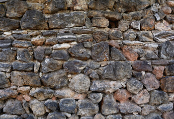 Irregular rough stone wall texture. Rocky grey and brown wallpaper design.