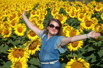 Young woman with outstretched arms in a field of sunflowers.