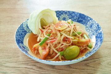 Som tum Thai spicy green papaya salad with fresh cabbage on plate