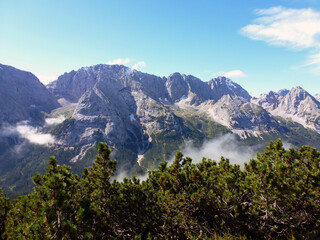 A high mountain with a blue horizon. In the foreground, the slope is covered with green forest. Beautiful natural landscape
