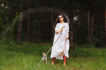 Young fashionable woman watering in the garden. Woman hand with garden hose watering plants, gardening concept.